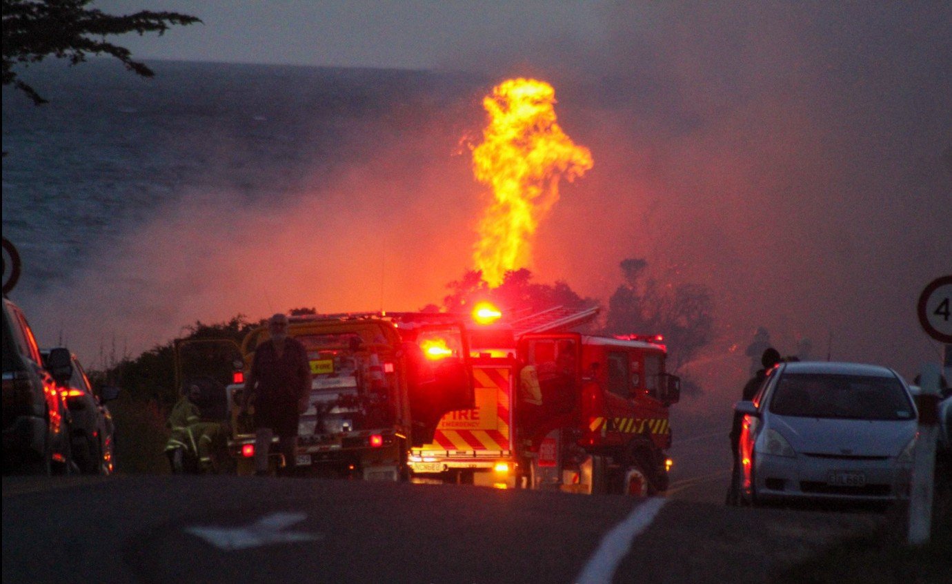 Onlookers watch as Fire and Emergency New Zealand crews battle a fire caused by fireworks that...