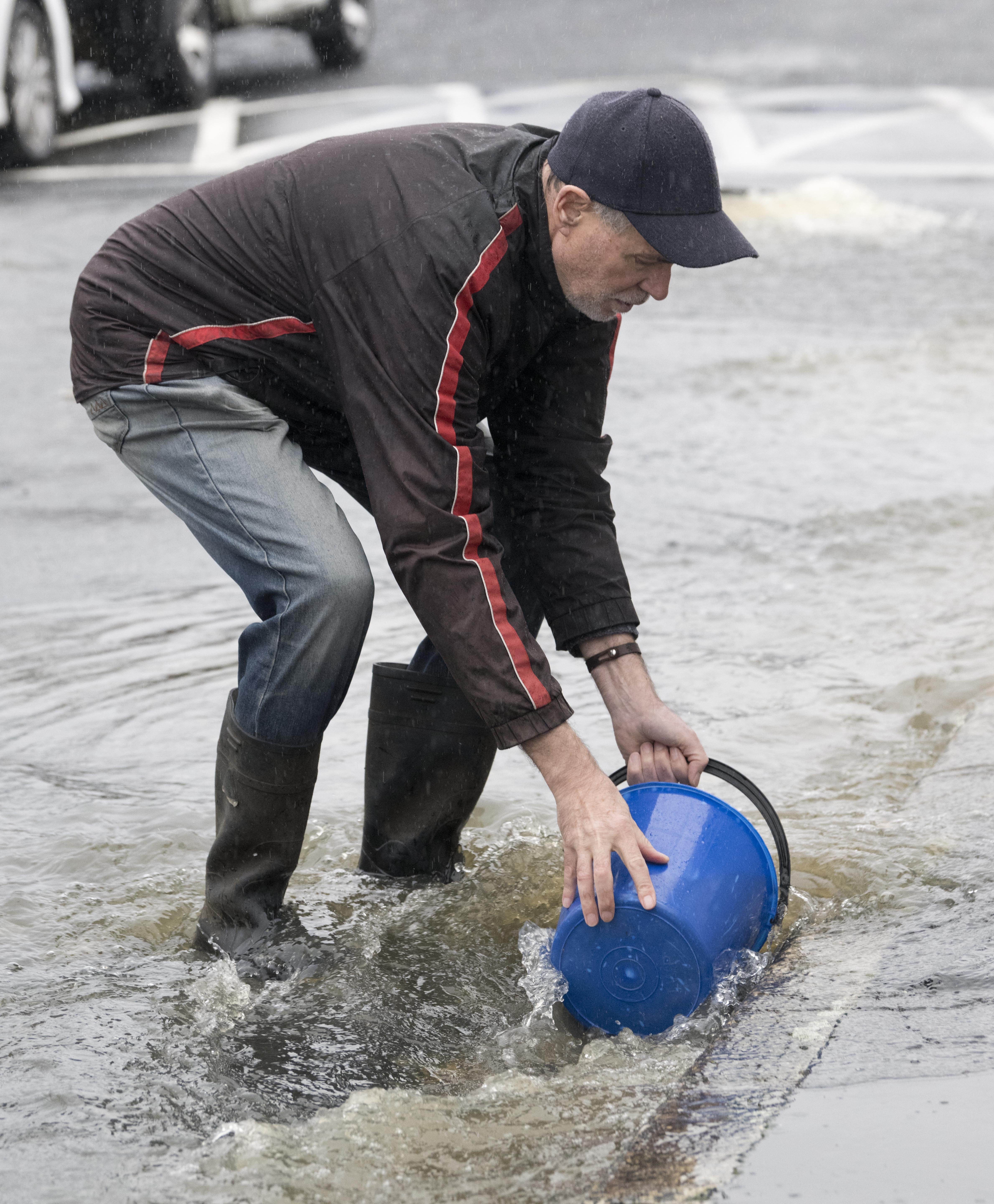 Surrey Street Flood Action Group member Julian Doorey collects a sample of the sewage water...