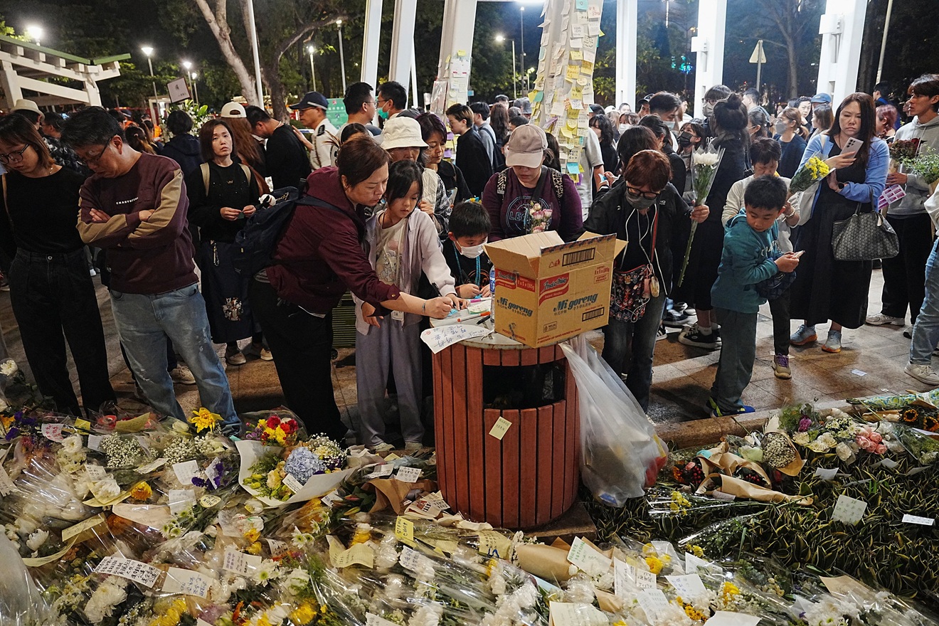 People pay tributes to victims of the fire at the Wang Fuk Court housing complex, in Tai Po, Hong...