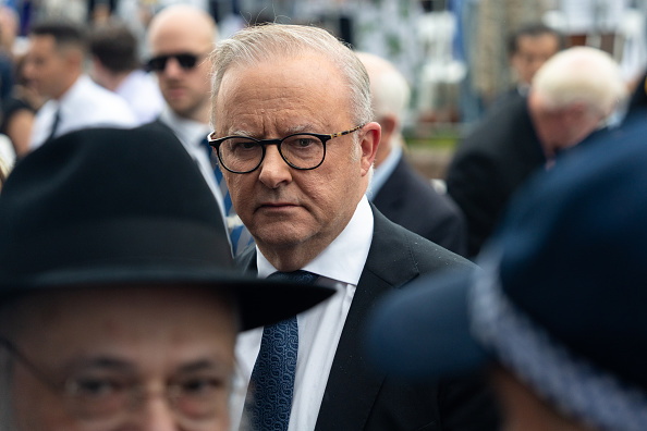 Australian Prime Minister Anthony Albanese stands between a rabbi and a police officer as...