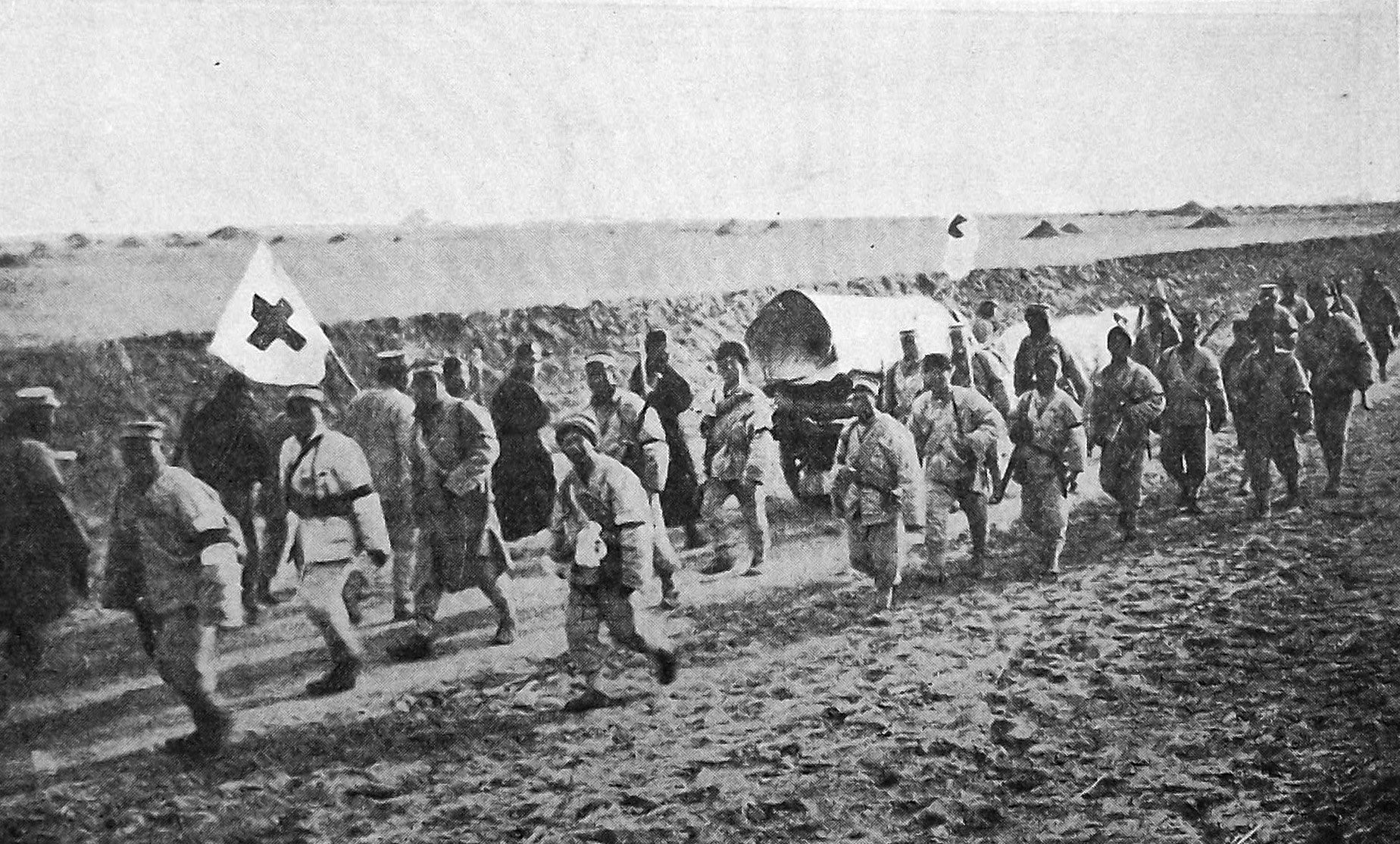 Wounded are evacuated under a Red Cross flag as reinforcements march to the front during the Anti...