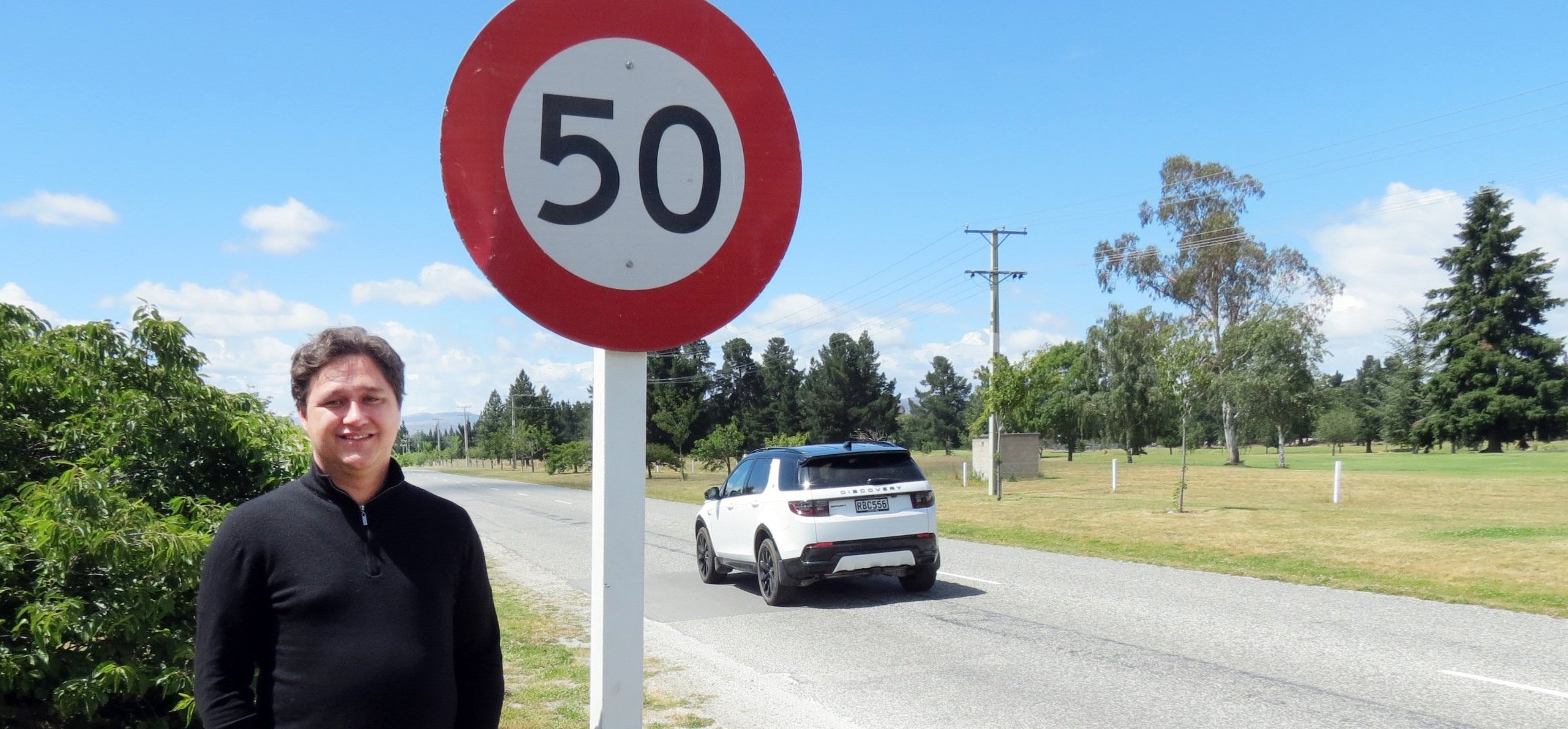 Vincent Community Board chairman Jayden Cromb poses with one of the new signs in Clyde replaced...