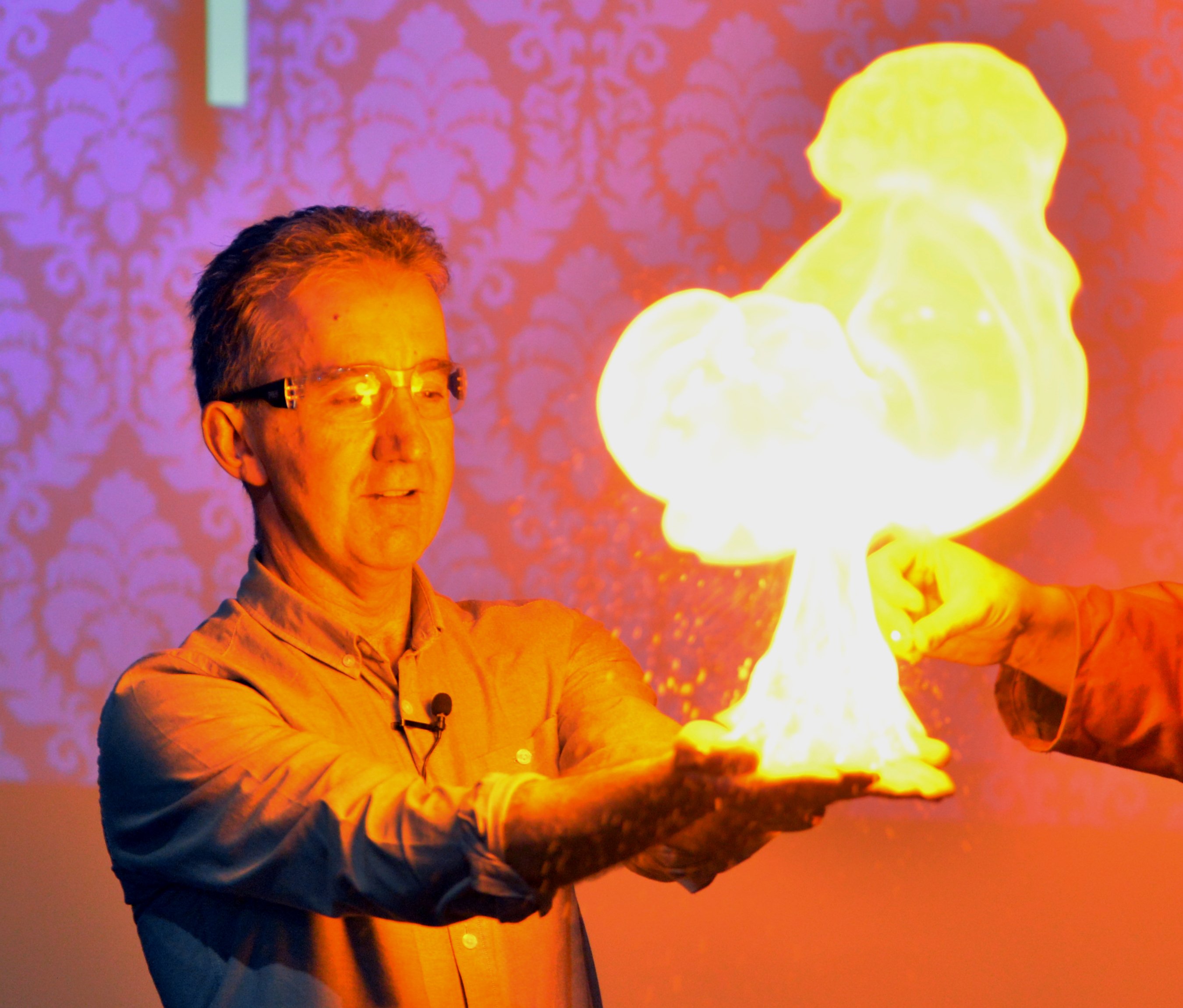 Nigel Latta watches hydrogen bubbles ignite from his hands during a science presentation at...