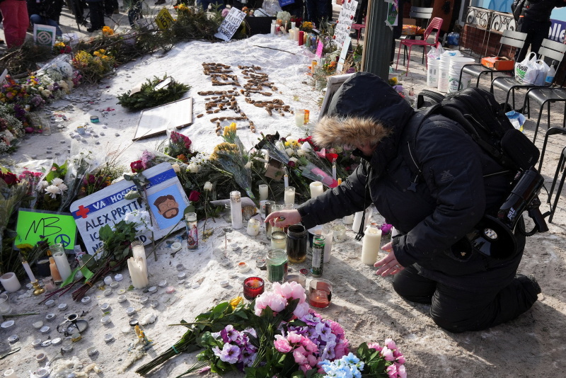 A person kneels at a makeshift memorial, at the site where a man identified as Alex Pretti was...