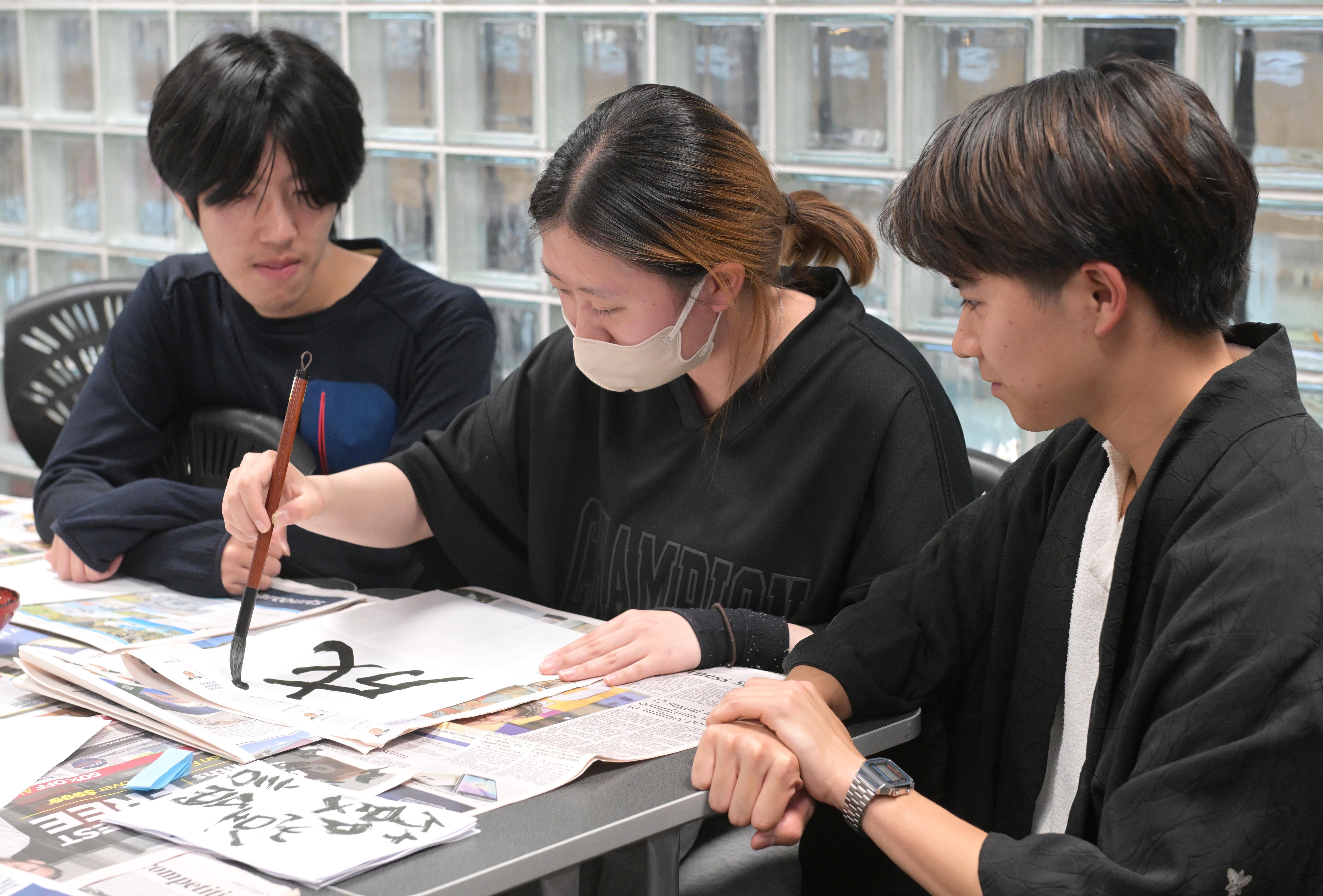 University of Otago Japanese student Maria Miya, 20, does some calligraphy while her peers Naoki...