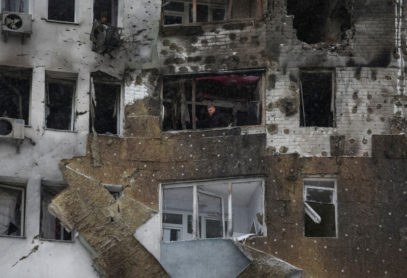 A resident stands on a balcony of his apartment, damaged during Russian drone strike, amid Russia...