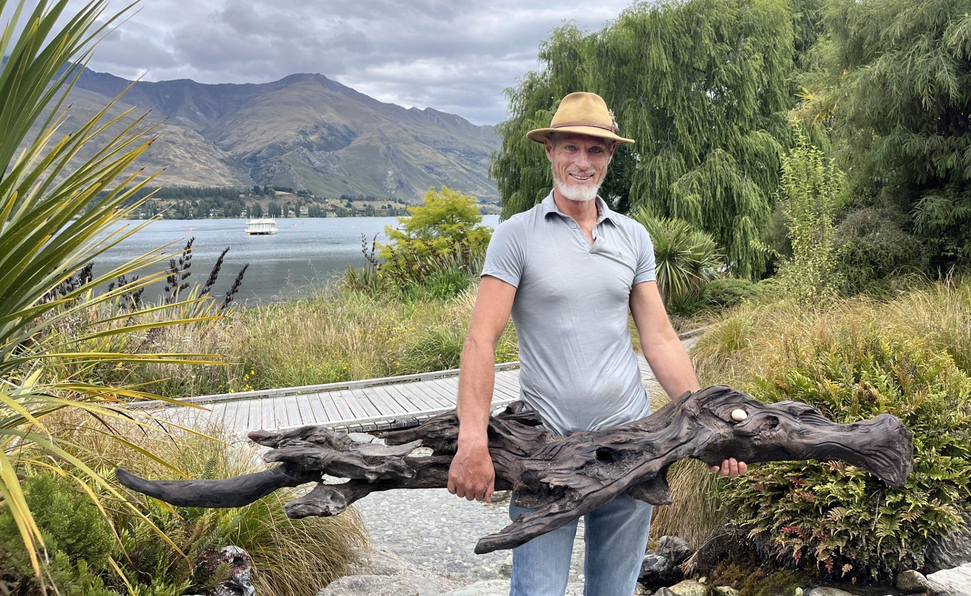 He holds his taniwha sculpture which he encourages children to name.