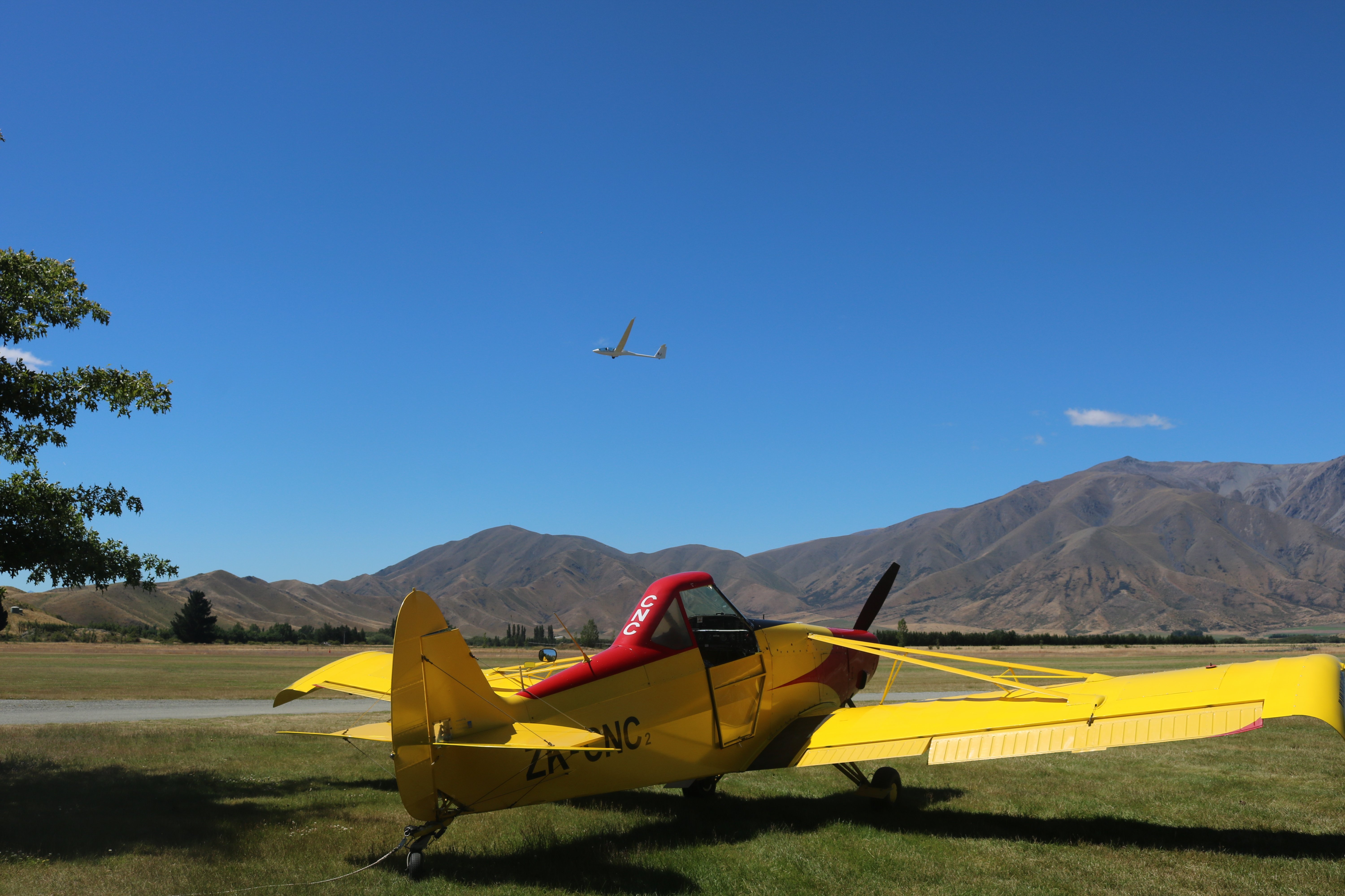 An aircraft soars above the Omarama Airfield near The Glider Cafe.