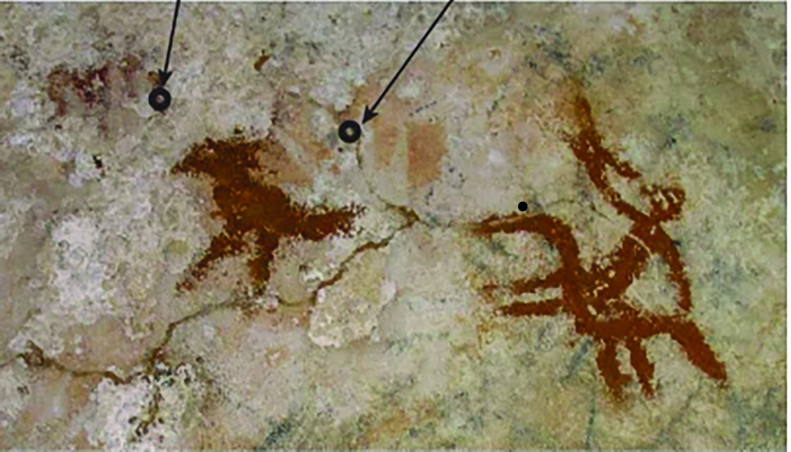 The arrows highlight the faded hand stencils dating back at least 67,800 years, the oldest known...
