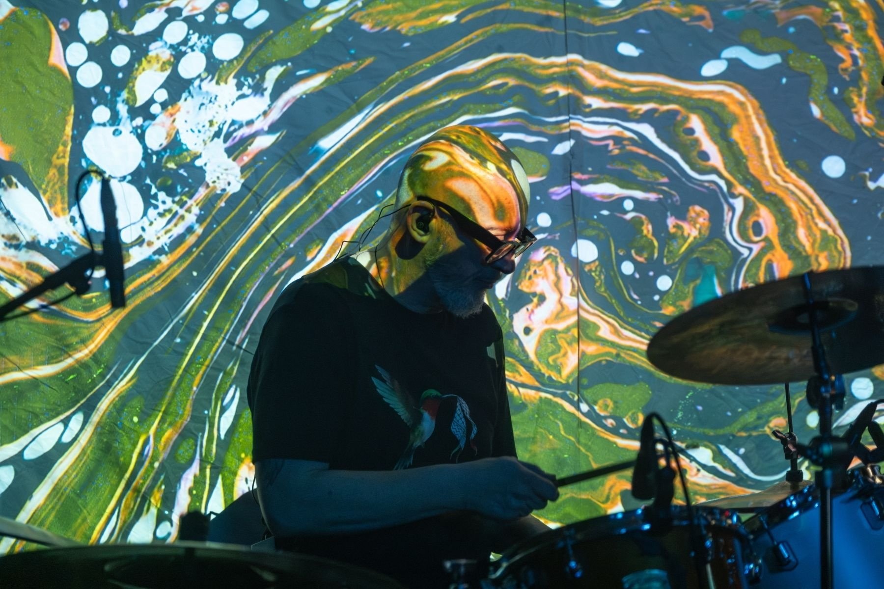 Ōtepoti psych-rock trio OMMU drummer Jeff Harford is part of the canvas for visual images in "The...