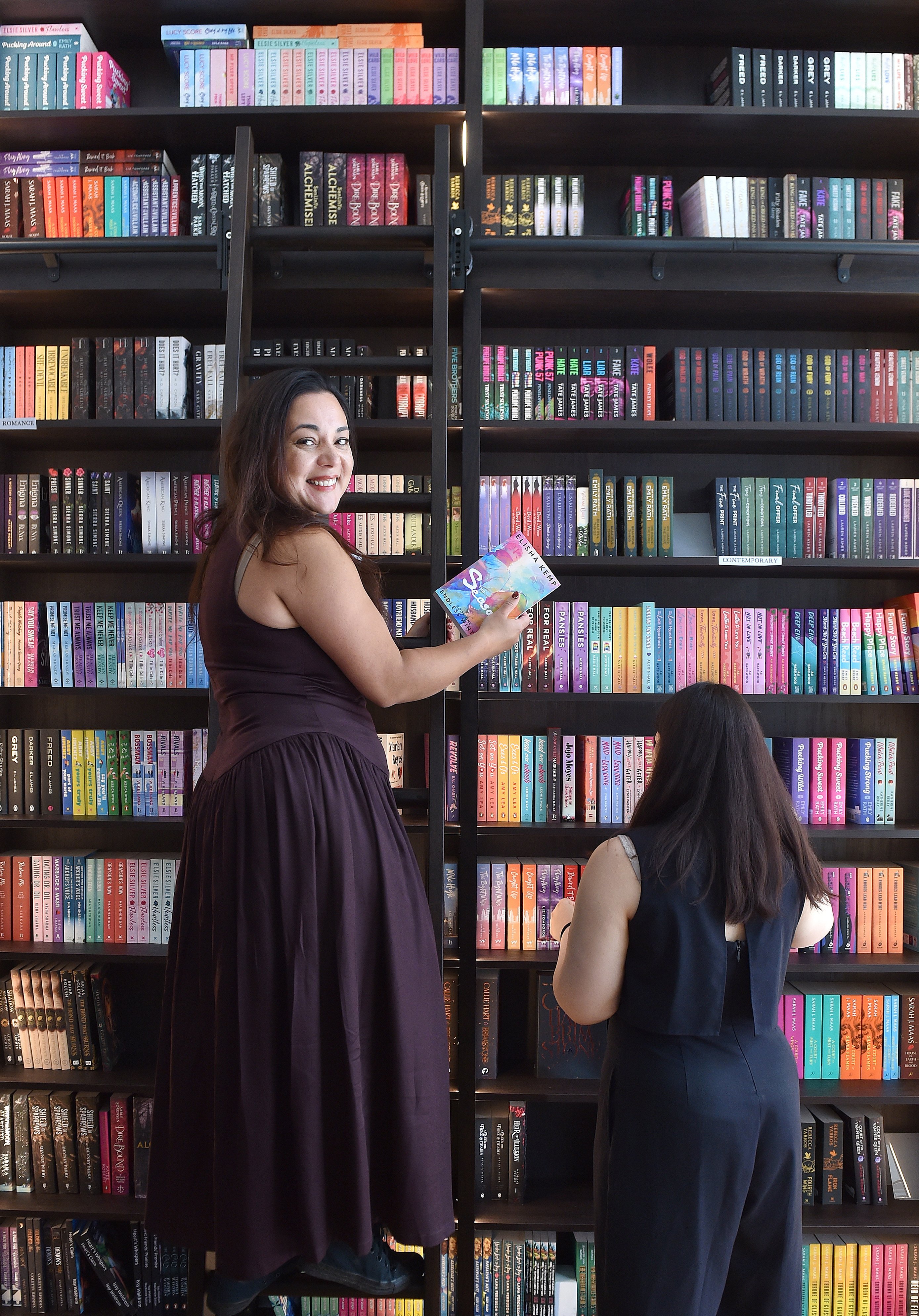 Colette Palmer, left, and Jasmine Begg, of The Ink Pot, use a rolling library ladder at the...