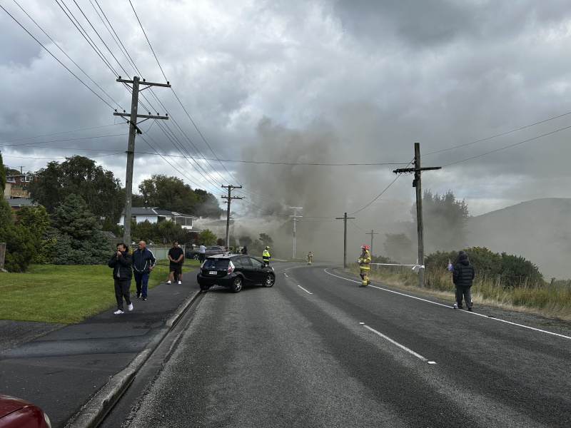 Smoke rises from a Concord house fire as emergency workers try to get people to clear the area....