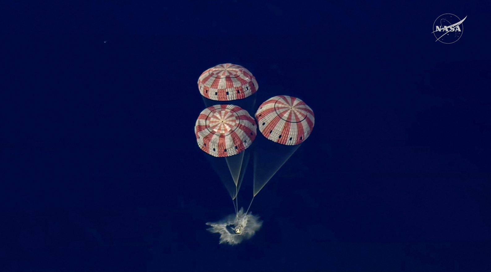 The Artemis II crew capsule splashes down in the Pacific Ocean in this screengrab from a...