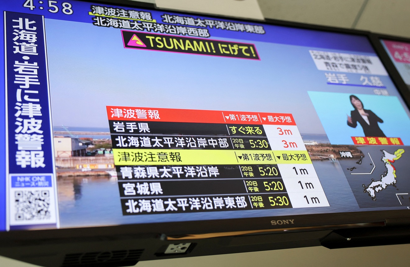 A television screen in Tokyo shows a news report on Japan Meteorological Agency's tsunami warning...