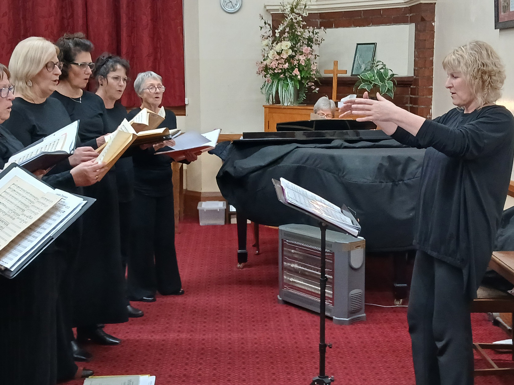 A Capella musical director Christine McLeod conducts the choir at a dress rehearsal in...