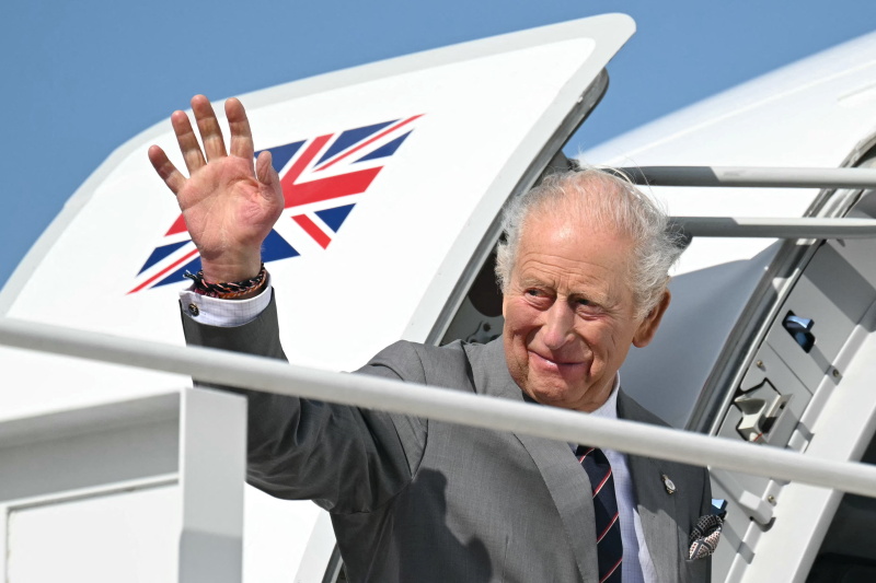 King Charles III wave as he boards his plane at Joint Base Andrews in Maryland as he wraps up his...