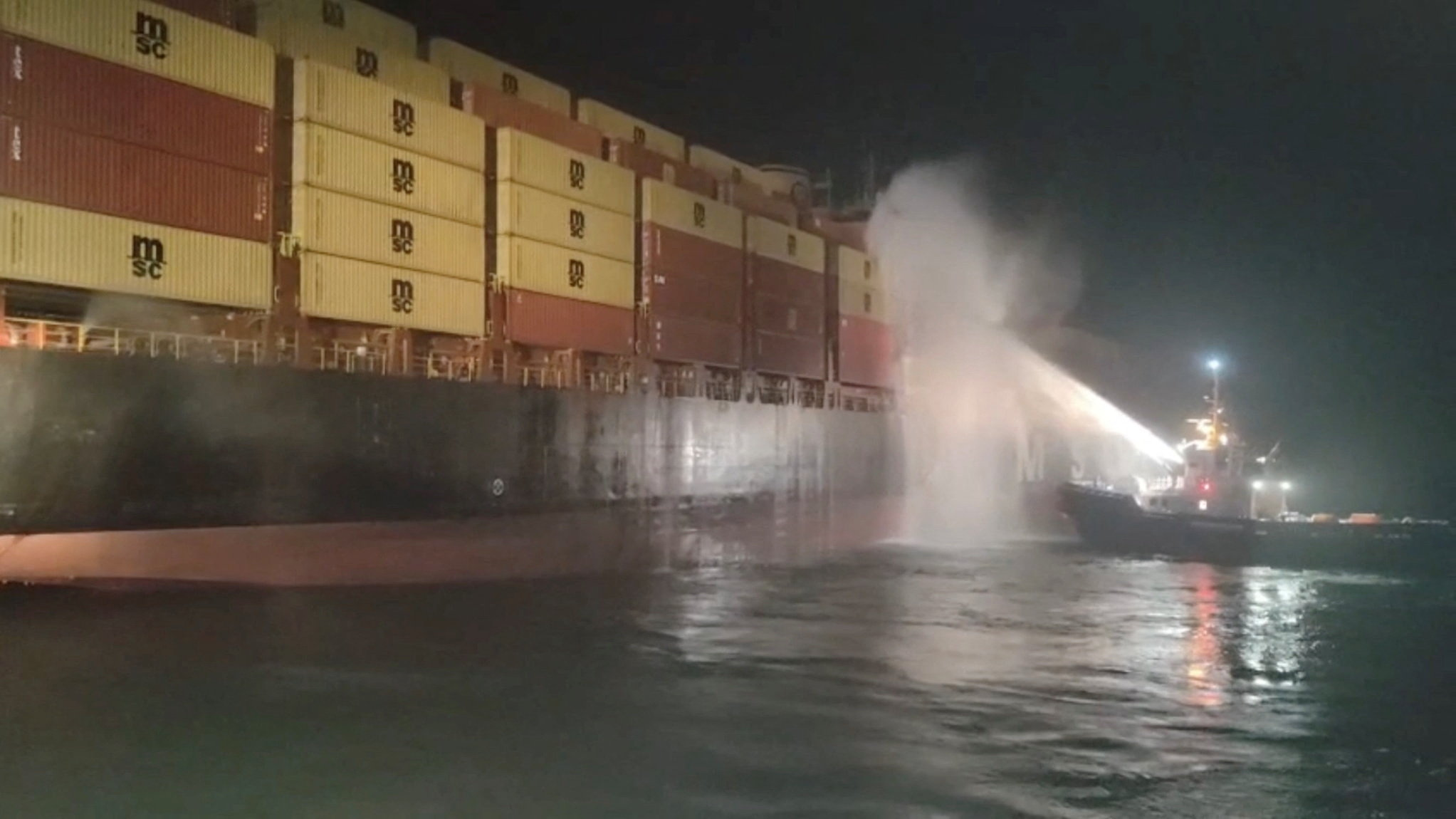 Personnel on a boat work to extinguish a fire on the Sariska V vessel in the Persian Gulf after...