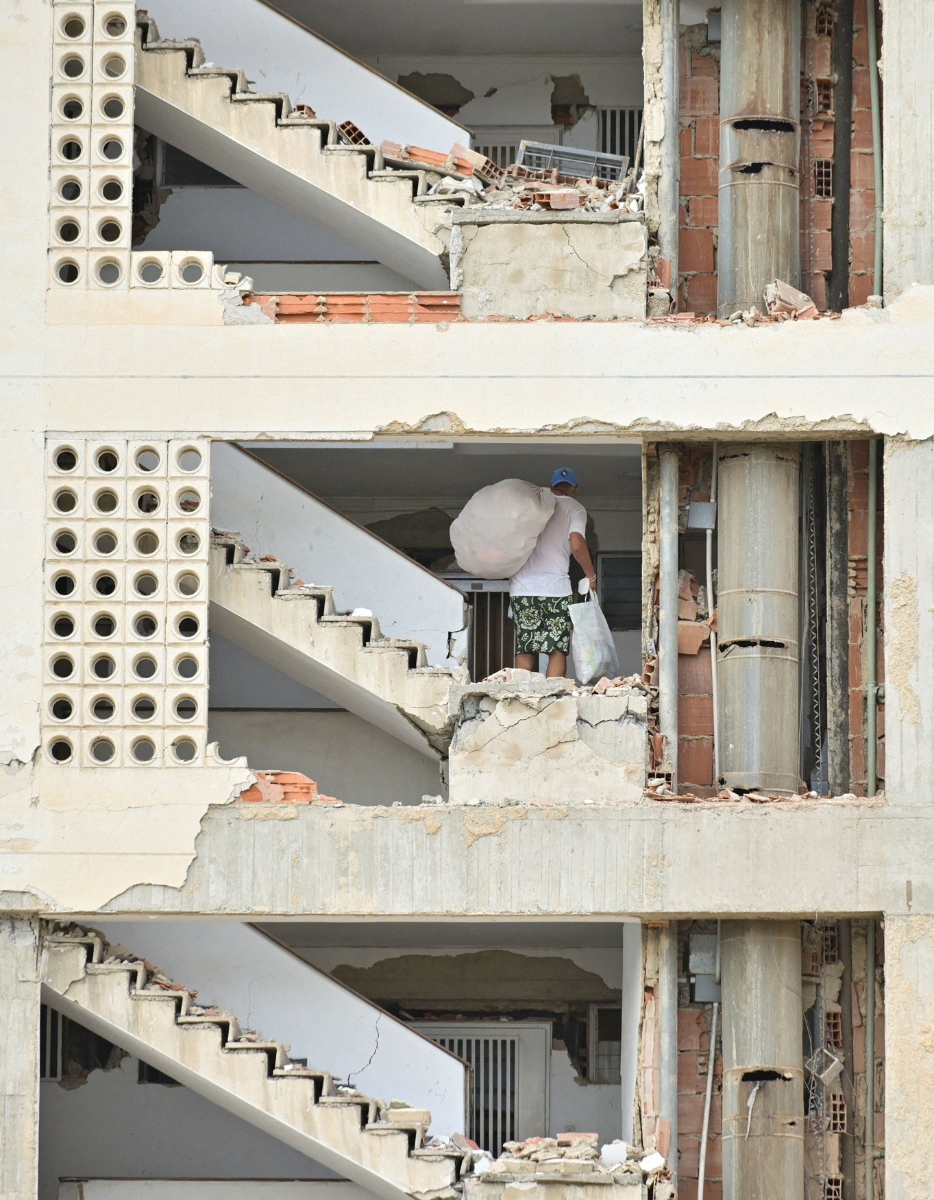 A man carrying belongings walks through a damaged building, after earthquakes hit La Guaira,...