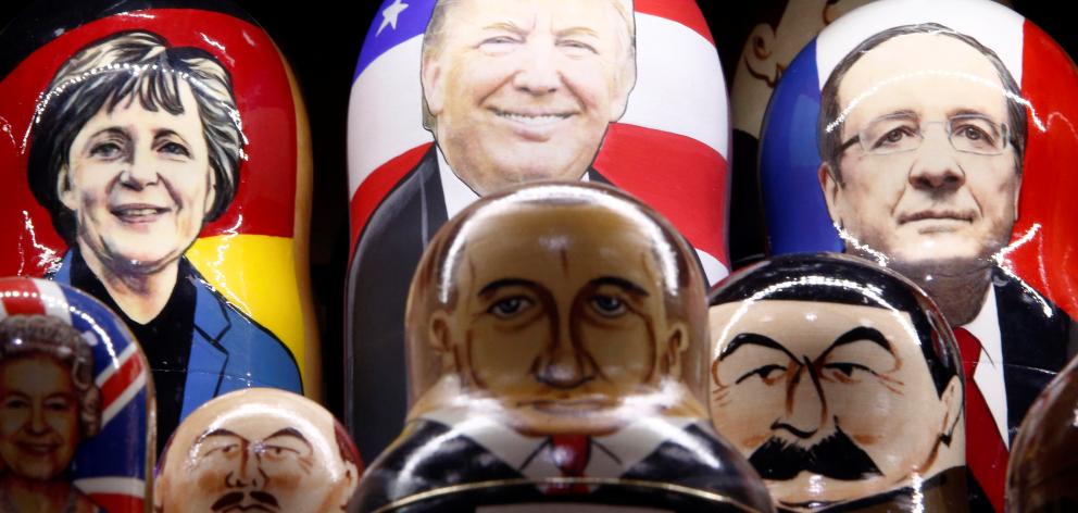 Painted Russian nesting dolls bearing the faces of (from top left): German Chancellor Angela...