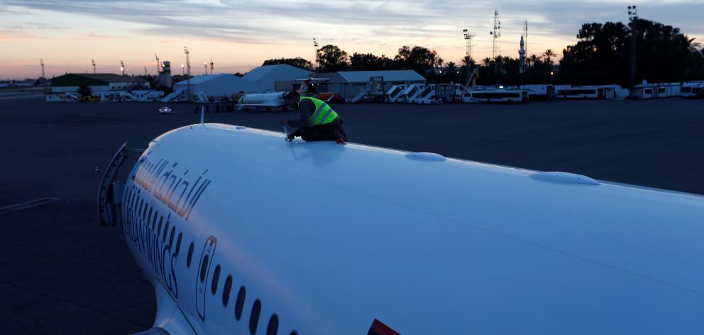 A worker checks a plane damaged at Mitiga airport in Tripoli. Photo: Reuters 