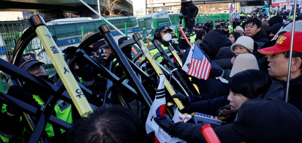 Supporters of President Yoon Suk Yeoll scuffle with police as authorities seek to execute an...
