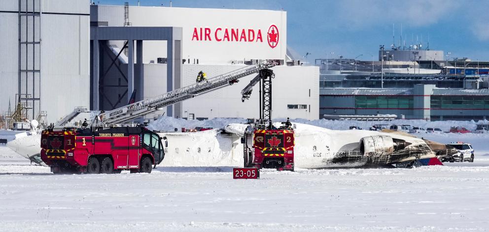 First responders work at the Delta Air Lines plane crash site at Toronto Pearson International...
