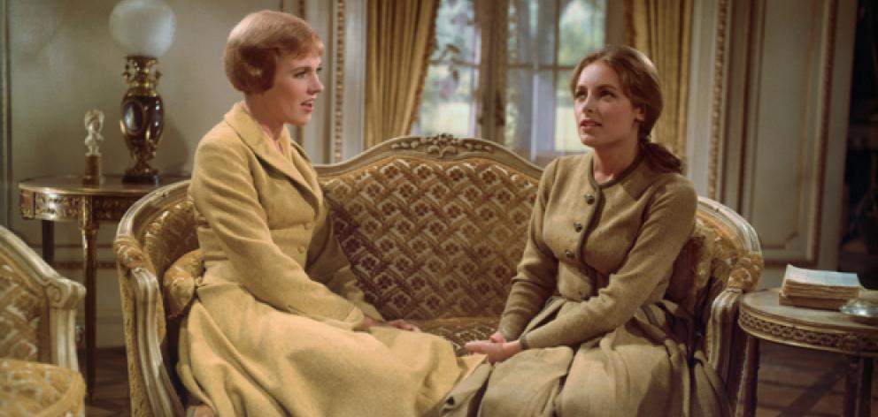 Julie Andrews as Maria von Trapp sits on a sofa with Charmian Carr as Liesl von Trapp in the...