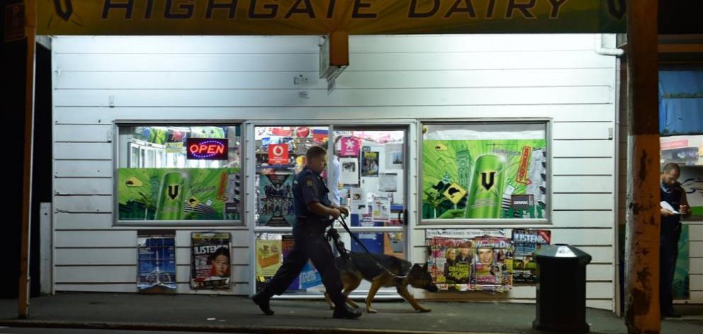 An officer using a dog attempts to track the masked assailant who robbed the Highgate Dairy. Photo: Peter McIntosh
