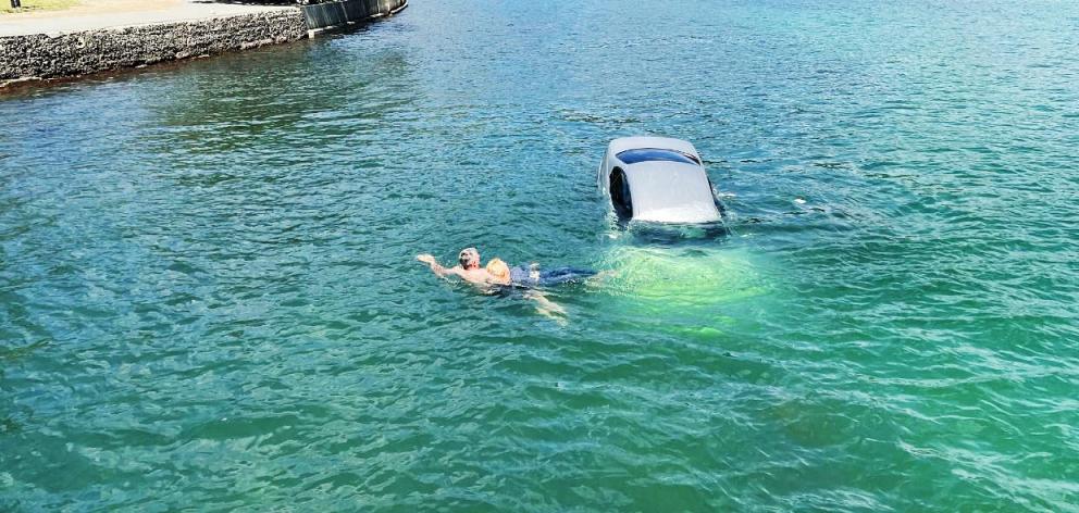 Tony Maw propels a woman to shore in Akaroa after rescuing her from a car. Photo: Supplied