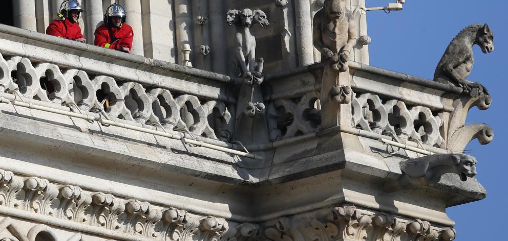 Firefighters at a balcony of the cathedral where gargoyles watch over Paris. Photo: AP