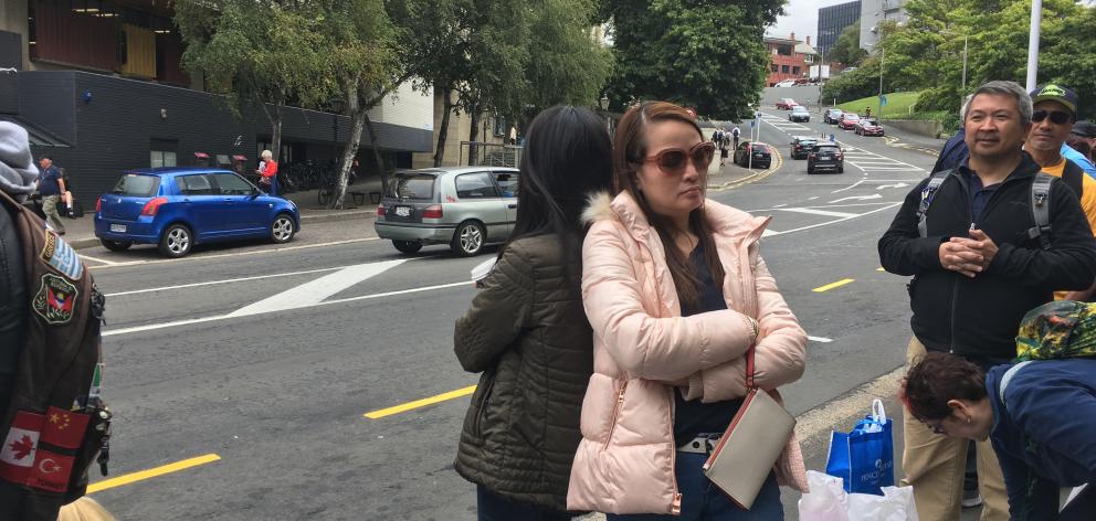 Cruise ship passengers, who did not want to be named, of Japan (left) and the Philippines, rest on each other when waiting for a bus in central Dunedin yesterday. PHOTO: SHAWN MCAVINUE 