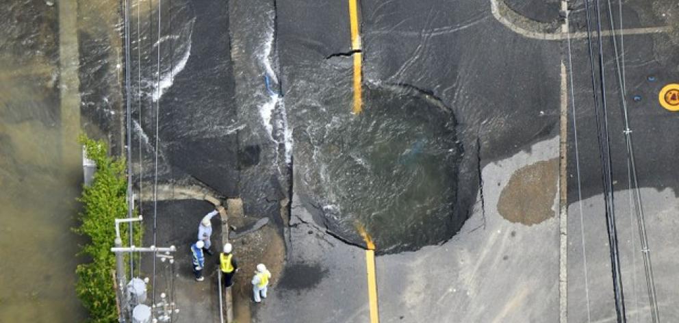 Water flows out from cracks in a road damaged by an earthquake in Takatsuki. Photo: Kyodo via Reuters