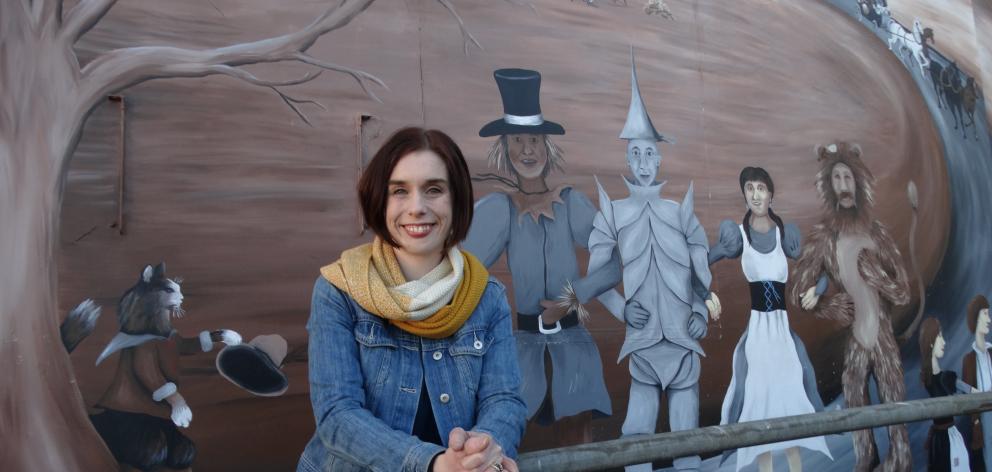 Dunedin Repertory Society vice-president Jemma Adams is flanked by the giant mural of characters...