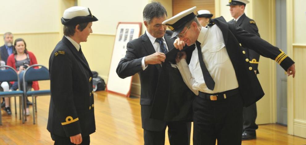 New Zealand Cadet Forces Lieutenant-commander Paul White (right) receives his newly decorated uniform jacket from Dunedin Mayor Dave Cull (centre) and Sub-lieutenant Elise Allen at the Port Chalmers Town Hall last night. Photo by Craig Baxter.