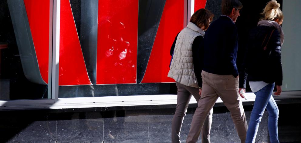 Pedestrians walk past a logo of the Westpac Bank Corp on display in a window of a branch. Photo:...