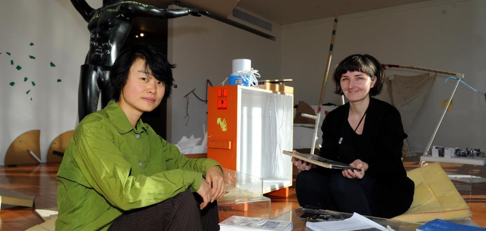 Auckland artist Xin Cheng and Dunedin Public Art Gallery curatorial intern Andrea Bell discuss the exhibition, surrounded by rejected items they hope people will use to create new things. Photo by Chris O'Connor.