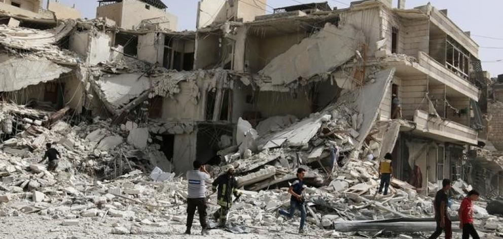 People inspect a damaged site after airstrikes on the rebel held al-Qaterji neighbourhood of...