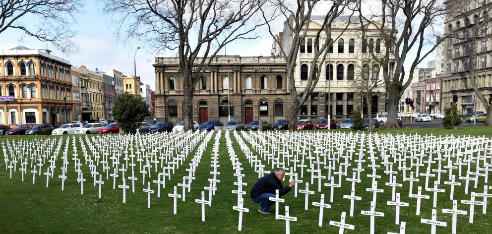 Juliana Barbosa, of Brazil, photographs the crosses placed in the Queens Gardens by the Cenotaph...