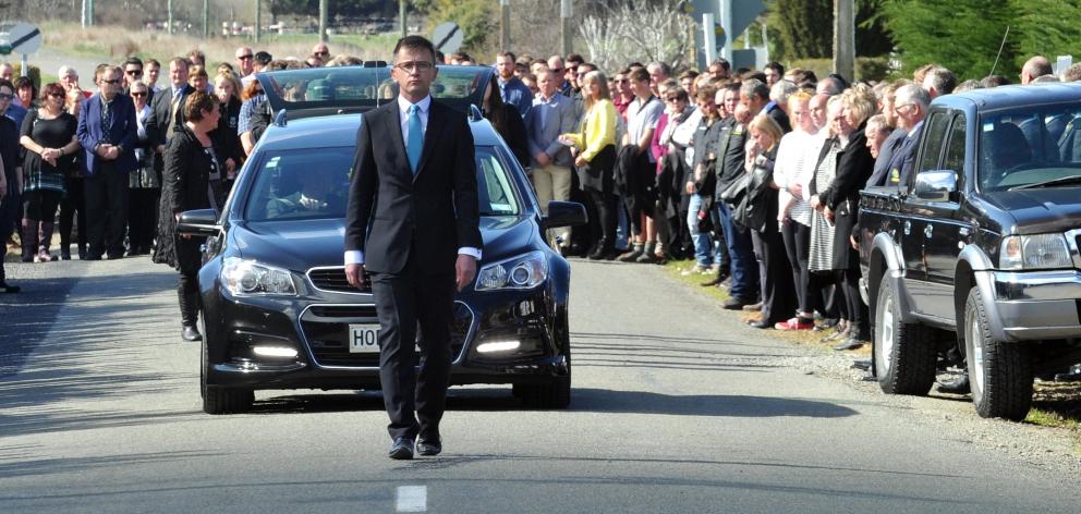 A guard of honour stretches down Horse Range Rd as the family of Andrew Grubb walk behind the...