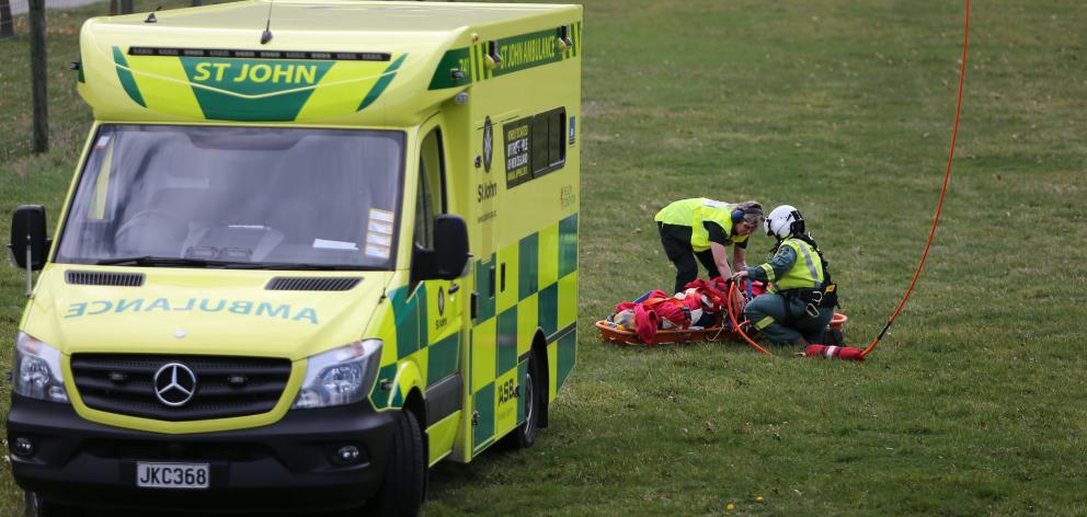 An ambulance officer and paramedic attend to a paraglider injured in a  crash, after he was...