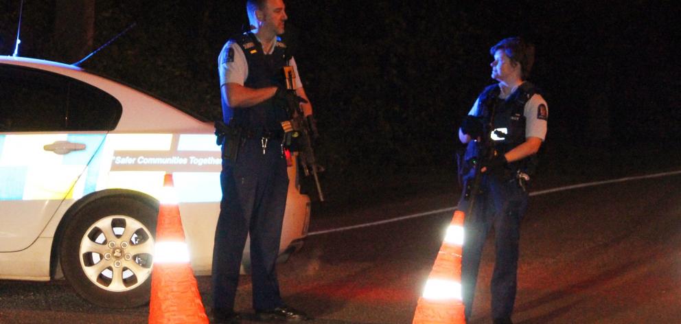 Armed police officers stop traffic at the intersection of Dunns and Otatara Rds on the outskirts...