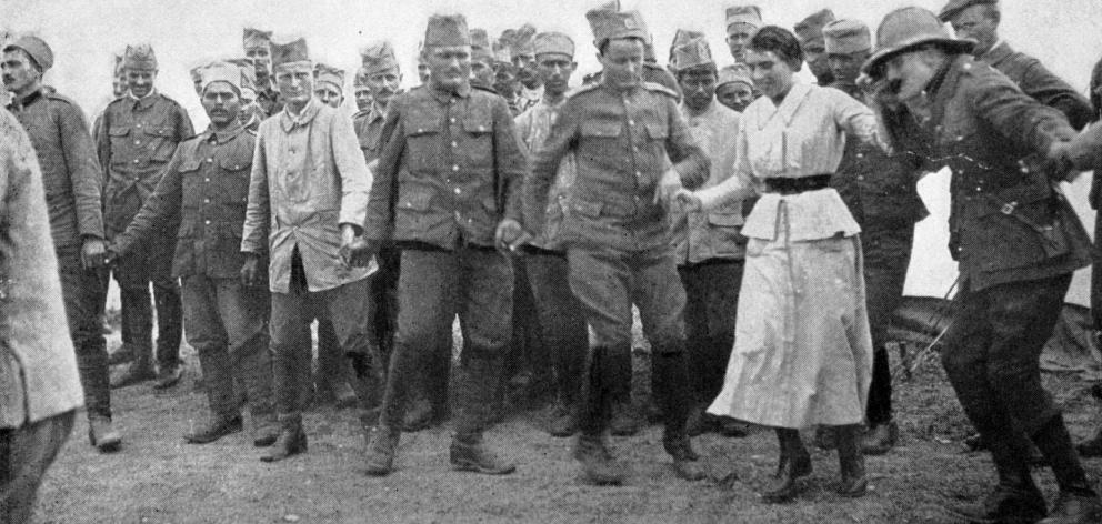 Serbian troops at Salonika dancing the "hora'' - a dance that lasts all day. The band is seated and are released one at a time for a spell. On this occasion British officers and a British lady Red Cross worker were invited to join in. - Otago Witness, 11.