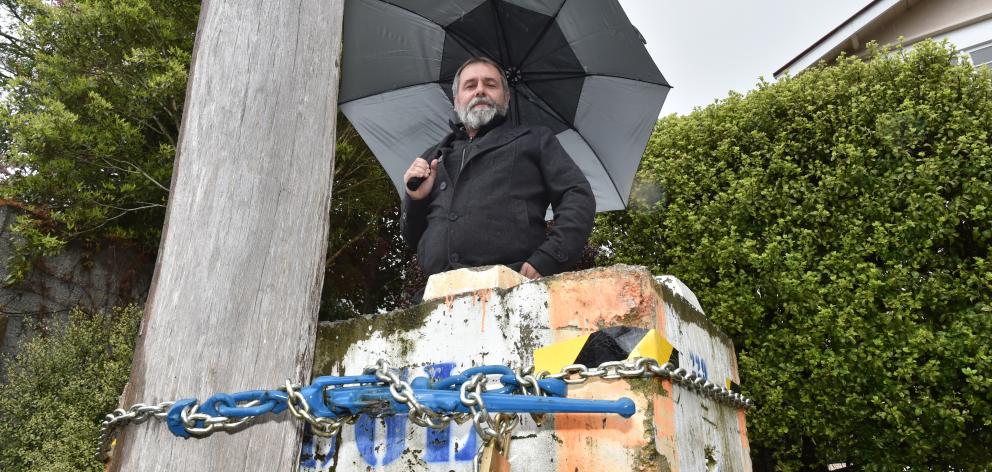 Richard Healey inspects  a power pole secured to a concrete block in Farley St yesterday ...
