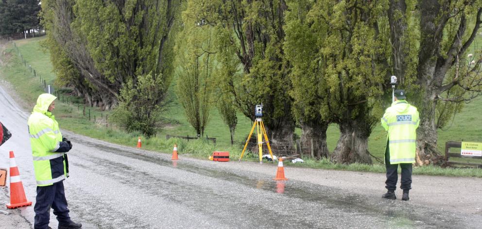 Constable Jack McGilbert (right), of the police serious crash unit, marks points in Ballantyne Rd, in Wanaka, as part of an investigation into Monday's fatal crash. Constable Greg Nolet, of Wanaka, controls traffic. Photo by Tim Miller.