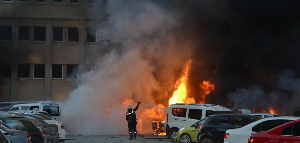 A firefighter tries to extinguish burning vehicles after an explosion outside the governor's...