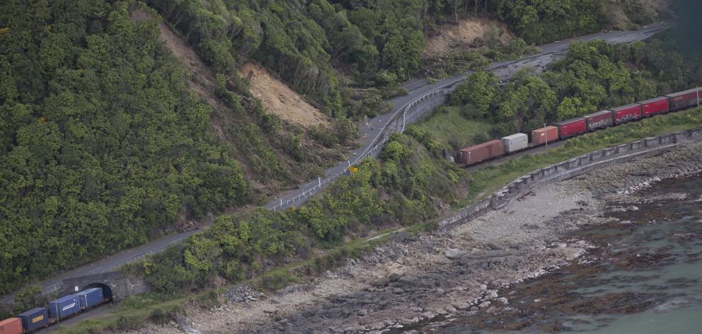 A freight train sits where it came to a halt beside State Highway 1, on the coast north of...