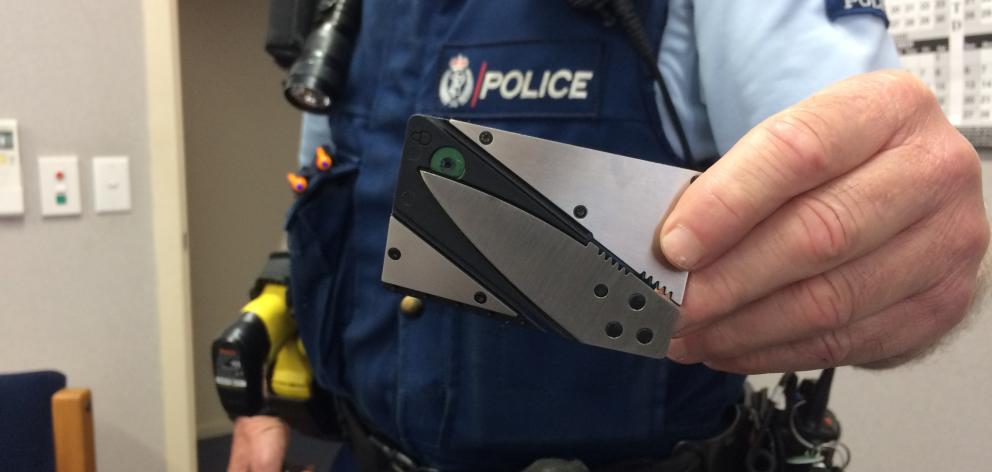 A police officer displays one of the collapsible knives in ``credit card form'' being distributed...