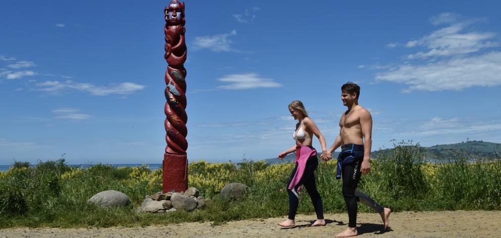 Georgia Manera (22), of Haast, and Angus Mackenzie (21), of Dunedin, walk past the new pou at Warrington Beach, which represents Tangaroa, the guardian of the ocean. Photo by Gregor Richardson.