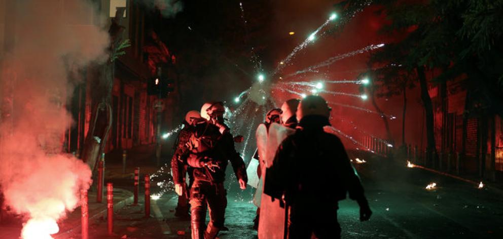 Fireworks explode next to riot police during clashes following an anniversary rally marking the...