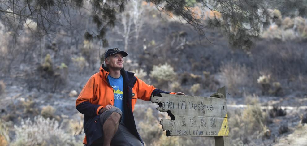 Hamish Seaton, of Mountain Biking Otago, inspects fire damage to a sign on Dunedin’s Signal Hill...